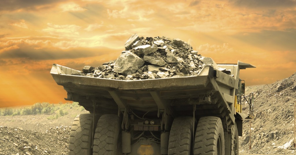 Heavy dump truck carrying the iron ore on the opencast mining on sunset